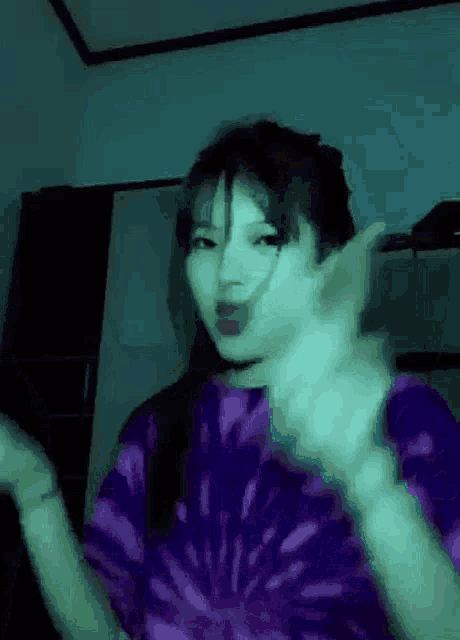 a girl in a purple tie dye shirt is dancing in a room .