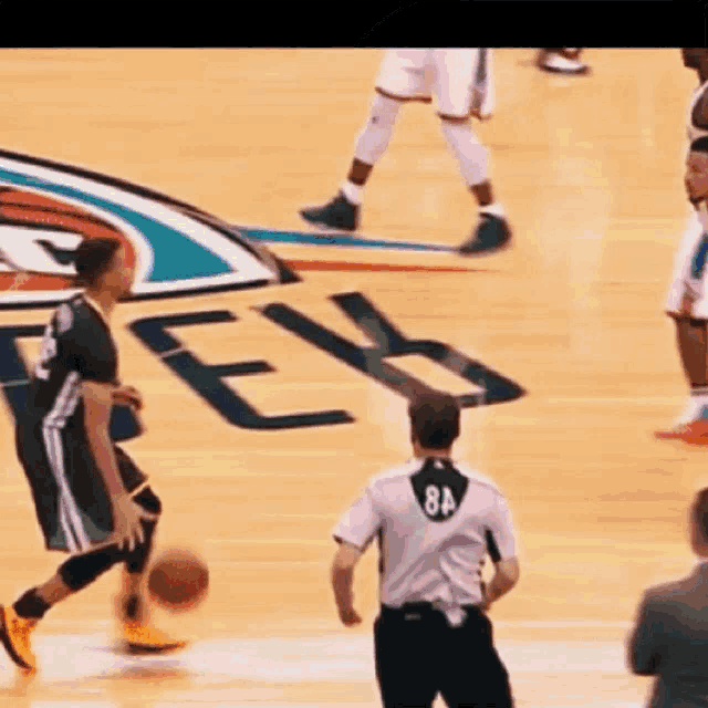 a referee with the number 84 on his back watches a basketball game
