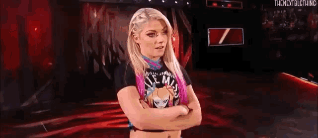 a woman is standing on a stage with her arms crossed and wearing a t-shirt .