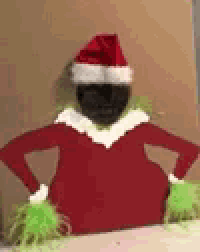 a black elf on the shelf is wearing a santa hat .