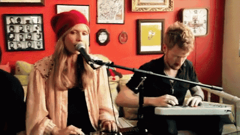 a woman singing into a microphone with a man playing a keyboard