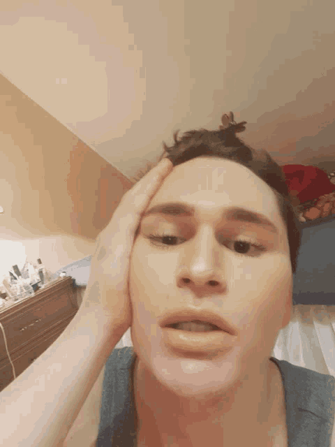 a man holds his hand to his forehead while making a face