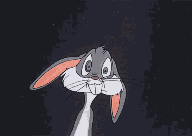 bugs bunny from the looney tunes cartoon is sitting down with his hands folded in front of his face .
