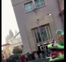 a blurry picture of a building with a green frog on the sidewalk