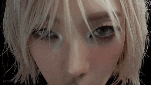 a close up of a woman 's face with blonde hair and blue eyes looking at the camera .