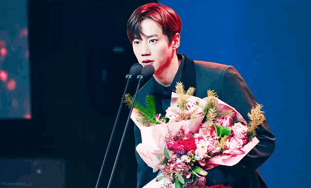 a man is holding a bouquet of flowers and speaking into a microphone with the word favor on the bottom