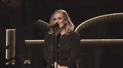 a woman in a black dress is singing into a microphone .