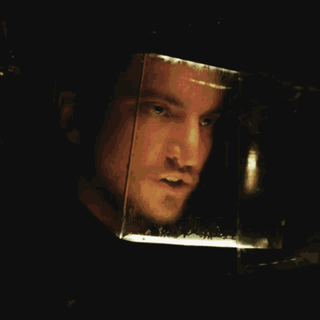 a close up of a man 's face in a glass box