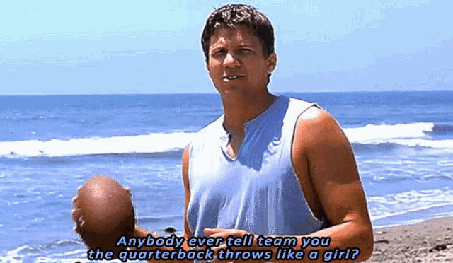 a man holding a football on a beach with the words anybody ever tell team you the quarterback throws like a girl