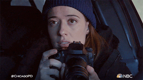 a woman is taking a picture with a camera while sitting in a car .