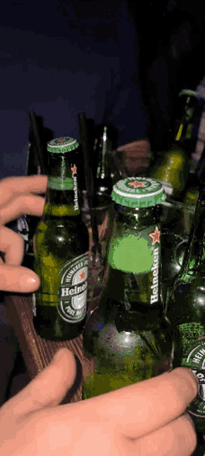a person is holding a bottle of heineken beer in their hand