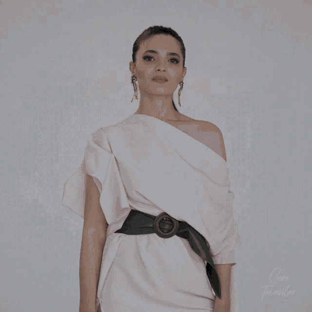 a woman wearing a white dress with a green belt and earrings stands in front of a white background with the words cami tavanlar