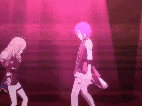 two anime characters are dancing on a stage in front of a crowd .