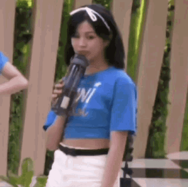 a woman in a blue shirt is holding a water bottle in her hand .