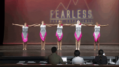 a group of dancers are performing in front of a fearless sign