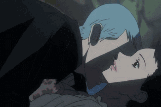 a man with blue hair is kissing a woman in a dark room