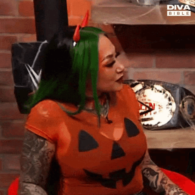 a woman with green hair and devil horns is wearing a diva bible shirt
