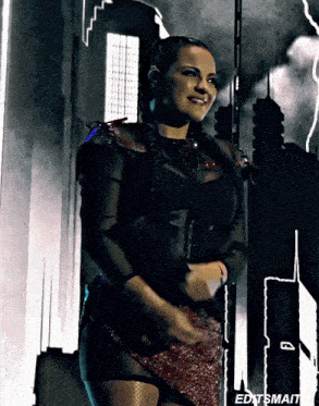 a woman in a black top and red skirt is smiling in front of a city skyline and the words editsmait on the bottom