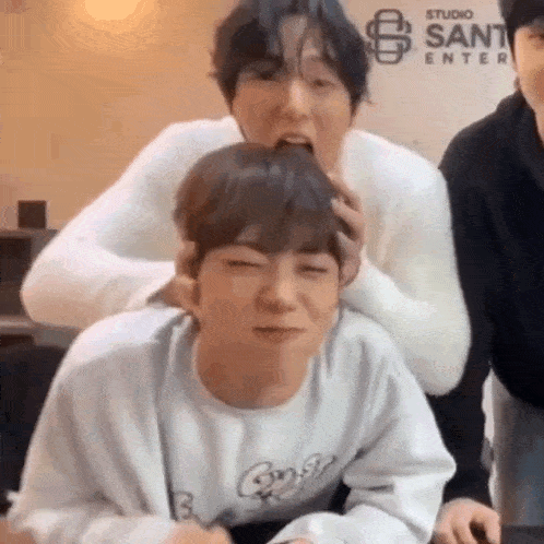 a group of young men are sitting next to each other and one of them is biting the other 's head .