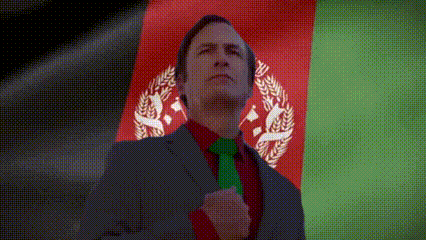 a man in a suit and green tie stands in front of a flag of afghanistan
