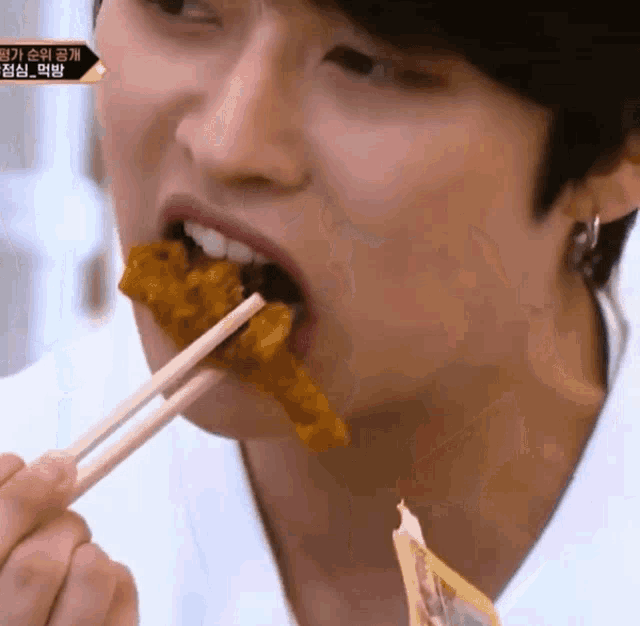 a close up of a person eating food with chopsticks with korean writing on the bottom