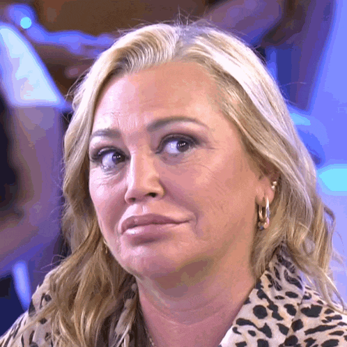a close up of a woman 's face with a leopard print shirt and hoop earrings