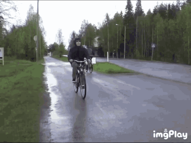a person riding a bike on a wet road with imgplay in the bottom right corner