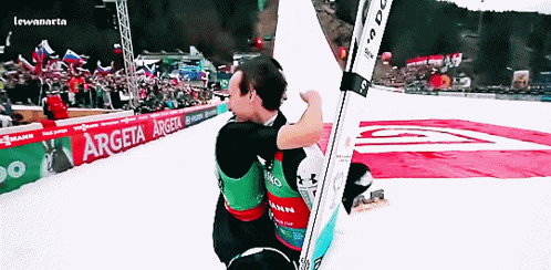 two skiers are hugging in front of a sign that says argeta