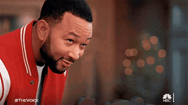 a man in a red jacket with #thevoice on the bottom
