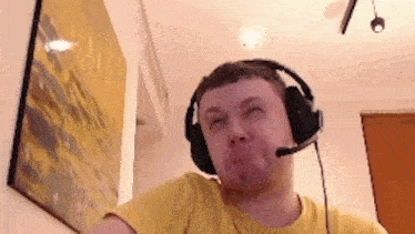 a man wearing headphones and a microphone is making a face .