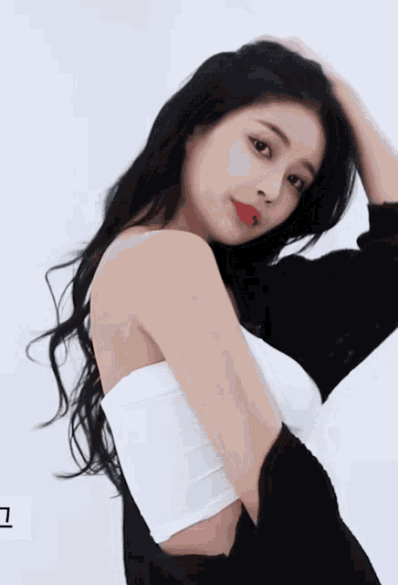 a woman with long black hair is wearing a white crop top and a black cardigan