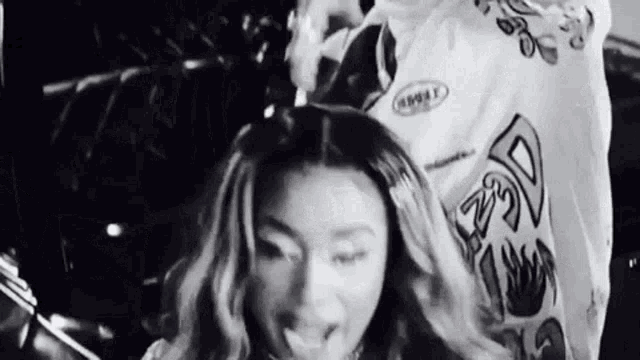 a black and white photo of a woman in a white shirt licking her lips .