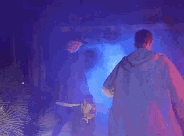 two men are standing in a dark room with purple smoke coming out of the walls