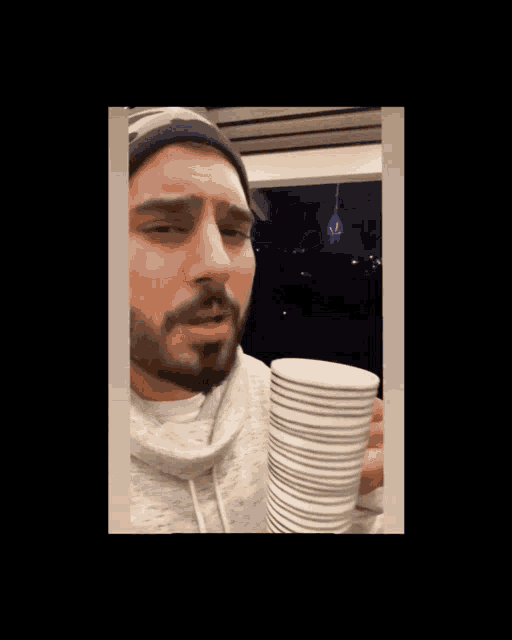 a blurry picture of a man holding a stack of plates in front of his face