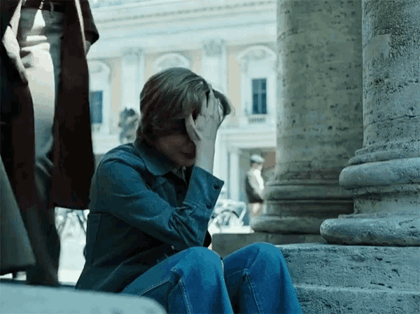 a man sits on the steps of a building with his head in his hands