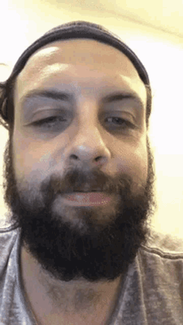 a man with a beard and a headband looks at the camera