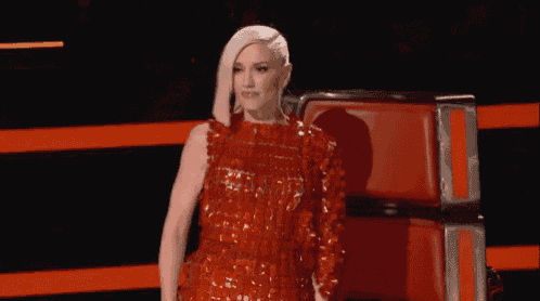 a woman in a red dress is sitting in a chair on stage .