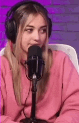a woman in headphones is sitting in front of a microphone .