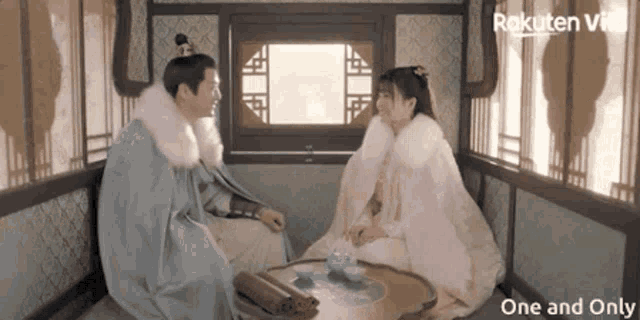 a man and a woman are sitting next to each other in a room with rakuten vi on the bottom