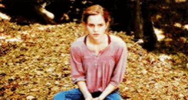 a woman is sitting on a pile of leaves in the woods