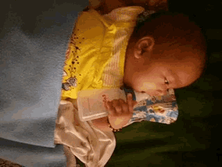 a baby is laying on a bed with a blanket and a bottle