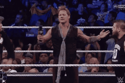 a man is standing in a wrestling ring holding a microphone and talking to another man .