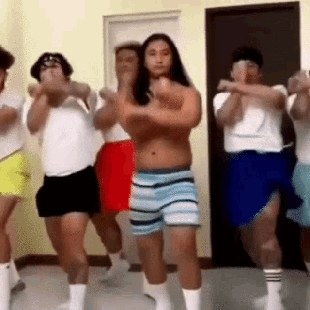 a group of men are dancing together in a room without shirts on .