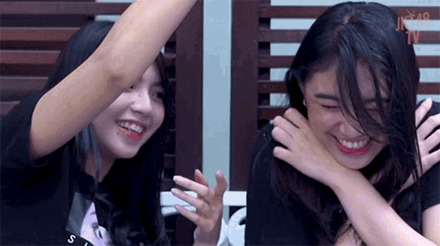 two girls are laughing and one has a tattoo on her arm