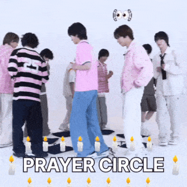 a group of young men are standing in a prayer circle with candles around them .