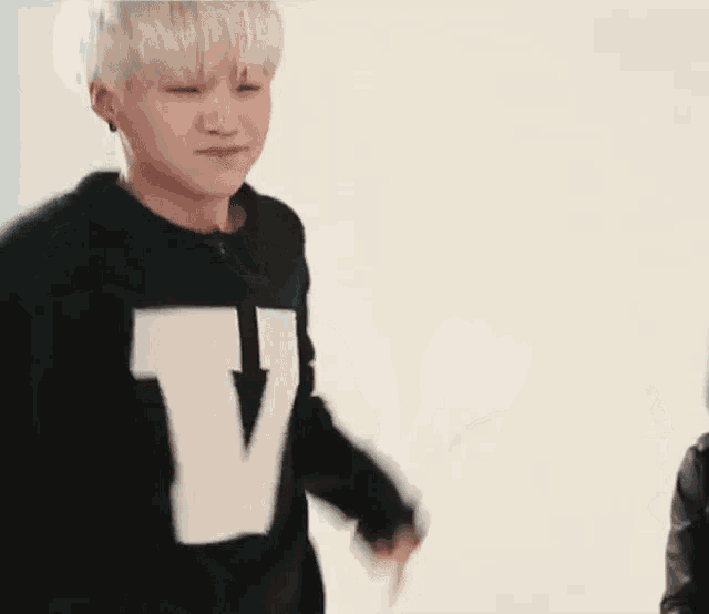 a young man wearing a black sweater with a white letter v on it