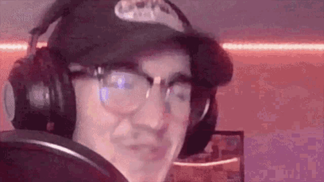 a man wearing headphones and a hat is standing in front of a microphone .