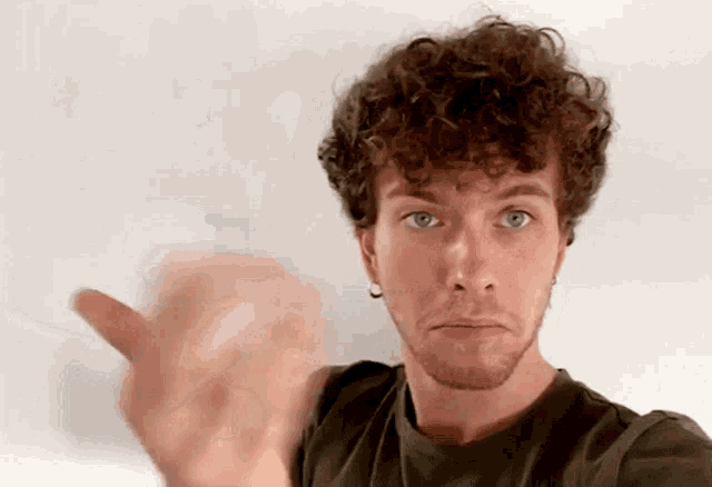 a man with curly hair and a beard is pointing