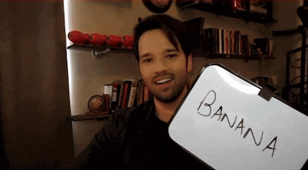 a man holds a white board that says banana on it