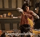 a woman is standing in a kitchen holding a broom and making a sandwich .